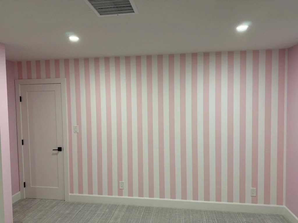 A room with pale pink and white striped wallpaper on the walls